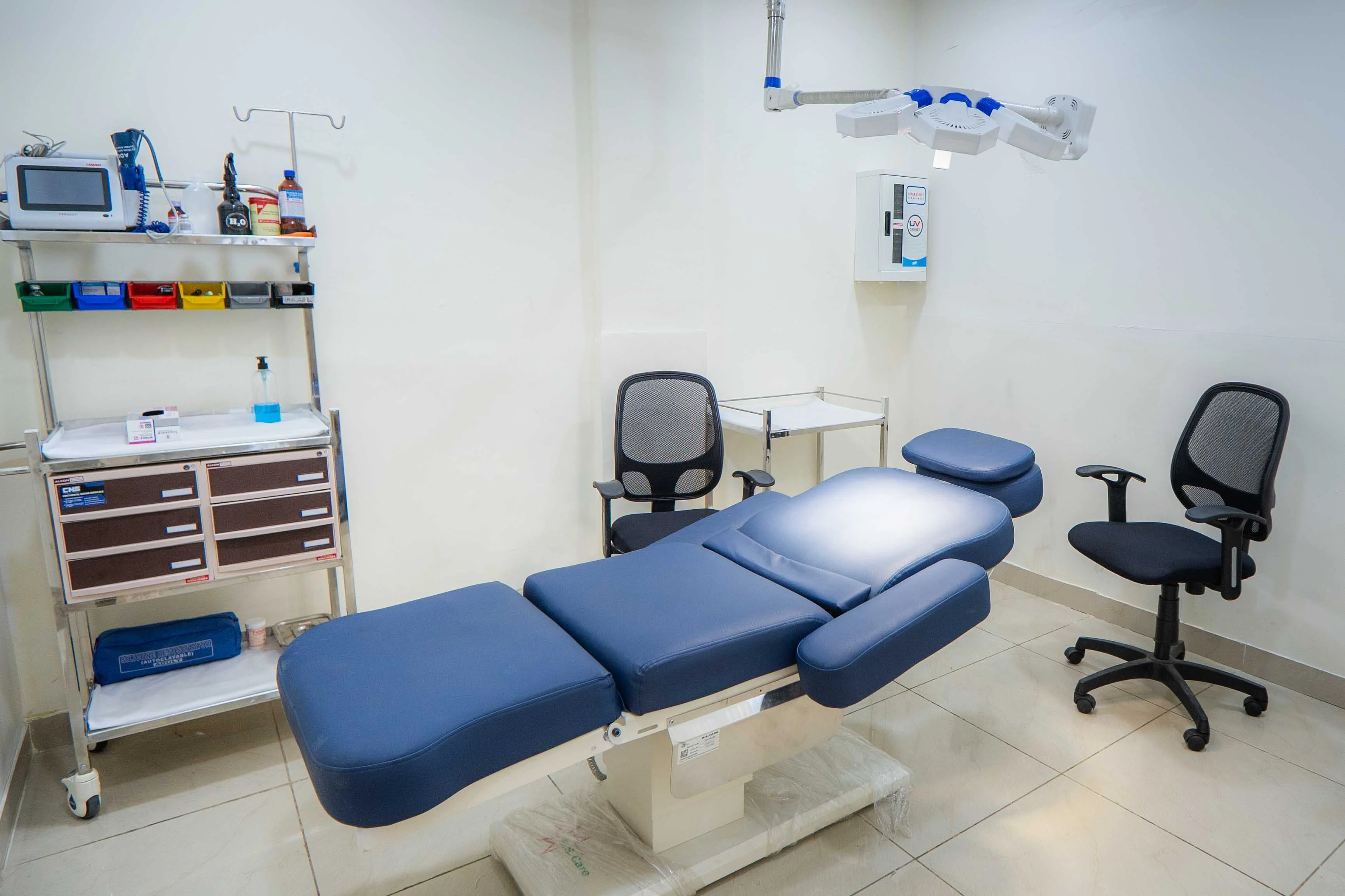 Procedure room with motorised bed and ceiling-arm UV steriliser lamp